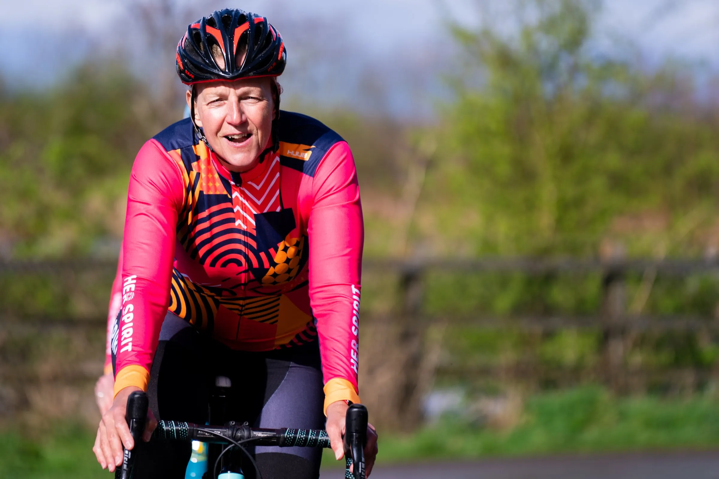A rider on a road bike wearing the long-sleeved HUUB Her Spirit cycle jersey